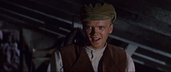 Movie still from “Journey to the Center of the Earth” (1959), directed by Henry Levin – A man wearing a hat and a brown vest smiling; Close Up shot, Low angle