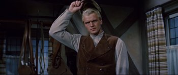 Movie still from “Journey to the Center of the Earth” (1959), directed by Henry Levin – A man in a brown vest holding his hat up; Close Up shot, Low angle