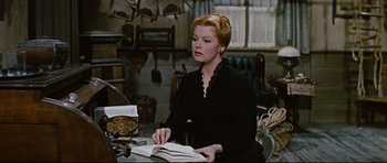 Movie still from “Journey to the Center of the Earth” (1959), directed by Henry Levin – A woman sitting at a table with a book; Medium shot, High angle