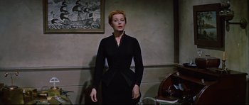 Movie still from “Journey to the Center of the Earth” (1959), directed by Henry Levin – A woman in a black dress standing in front of a wall; Medium shot, Low angle