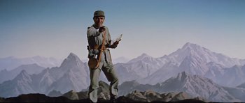 Movie still from “Journey to the Center of the Earth” (1959), directed by Henry Levin – A man standing on top of a mountain holding a map; Medium shot, Low angle