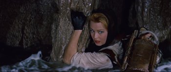 Movie still from “Journey to the Center of the Earth” (1959), directed by Henry Levin – A woman with a black glove is leaning against a tree trunk; Medium shot, Overhead angle