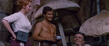 Movie still from “Journey to the Center of the Earth” (1959), directed by Henry Levin – A shirtless man is holding a bowl in his hands; Medium shot, Over the shoulder angle
