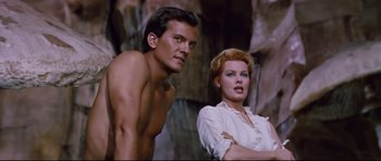 Movie still from “Journey to the Center of the Earth” (1959), directed by Henry Levin – A man and a woman standing next to each other in front of rocks; Medium shot, Low angle