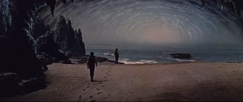 Movie still from “Journey to the Center of the Earth” (1959), directed by Henry Levin – Two people walking on the beach near the water; Extreme Wide shot, High angle