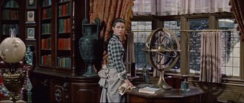 Movie still from “Journey to the Center of the Earth” (1959), directed by Henry Levin – A woman standing next to an old fashioned clock; Medium shot, Low angle