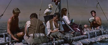 Movie still from “Journey to the Center of the Earth” (1959), directed by Henry Levin – A man sitting on top of a boat next to a bird; Medium shot, High angle
