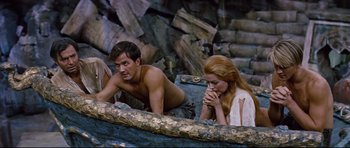 Movie still from “Journey to the Center of the Earth” (1959), directed by Henry Levin – A man and a woman sitting next to each other on rocks; Medium shot, High angle