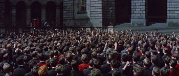 Movie still from “Journey to the Center of the Earth” (1959), directed by Henry Levin – A crowd of people sitting in front of a brick building; Extreme Wide shot, High angle
