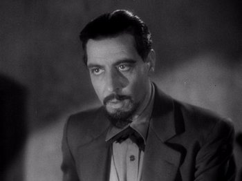 Movie still from “Juarez” (1939), directed by William Dieterle – Black and white photograph of a man in a suit and bow tie; Close Up shot, Low angle