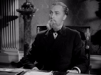 Movie still from “Juarez” (1939), directed by William Dieterle – A man sitting at a desk with a beard on top of his head; Close Up shot, Low angle