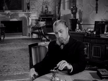 Movie still from “Juarez” (1939), directed by William Dieterle – A man sitting at a table with a knife in his hand; Medium shot, High angle
