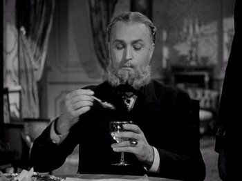 Movie still from “Juarez” (1939), directed by William Dieterle – A man with a goatee and a beard is holding a glass of wine; Close Up shot, Low angle