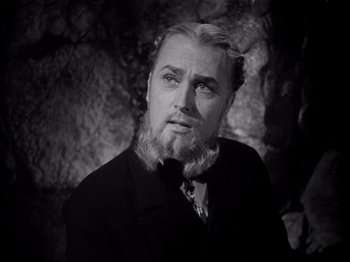 Movie still from “Juarez” (1939), directed by William Dieterle – A man with a long beard is standing in front of a rock wall; Close Up shot, Low angle