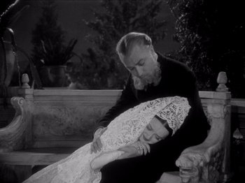 Movie still from “Juarez” (1939), directed by William Dieterle – An older man and a younger woman sitting on a bench; Medium shot, High angle