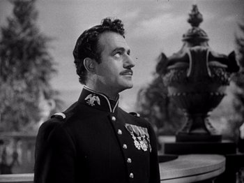 Movie still from “Juarez” (1939), directed by William Dieterle – A man in a military uniform stands in front of a statue; Close Up shot, Low angle