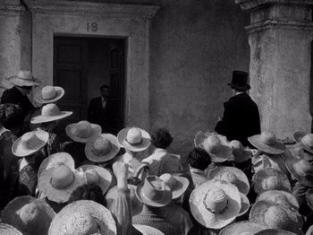 Movie still from “Juarez” (1939), directed by William Dieterle – A group of people wearing hats in front of a building; Wide shot, High angle