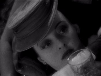 Movie still from “Juarez” (1939), directed by William Dieterle – A black and white photo of a woman drinking a glass of beer; Close Up shot, High angle