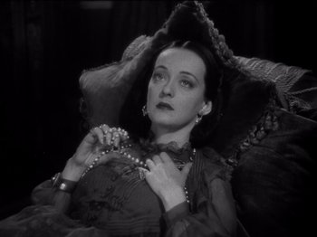 Movie still from “Juarez” (1939), directed by William Dieterle – A woman sitting in a chair holding a string of pearls; Close Up shot, High angle