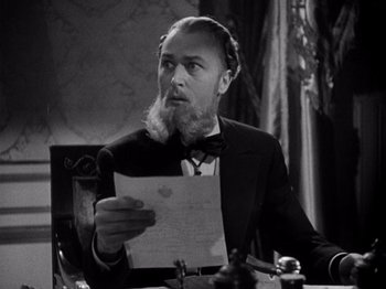 Movie still from “Juarez” (1939), directed by William Dieterle – A man sitting at a table holding a piece of paper; Close Up shot, Low angle