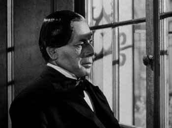 Movie still from “Juarez” (1939), directed by William Dieterle – A man in a black suit sitting in front of a window; Close Up shot, Low angle