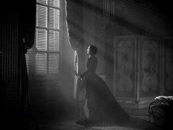 Movie still from “Juarez” (1939), directed by William Dieterle – A woman in a long dress standing in front of a window; Wide shot, Low angle