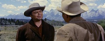 Movie still from “Jubal” (1956), directed by Delmer Daves – Two men in cowboy hats talking to each other in front of mountains; Medium shot, Over the shoulder angle
