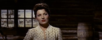 Movie still from “Jubal” (1956), directed by Delmer Daves – A woman in a polka dot shirt is standing in front of a window; Close Up shot, Low angle