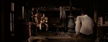 Movie still from “Jubal” (1956), directed by Delmer Daves – A man sitting on a chair in a room; Wide shot, High angle