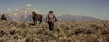 Movie still from “Jubal” (1956), directed by Delmer Daves – A man in a cowboy hat is standing in a field with two horses; Wide shot, Low angle