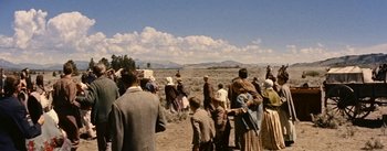 Movie still from “Jubal” (1956), directed by Delmer Daves – A group of people standing on top of a dry grass field; Extreme Wide shot, High angle