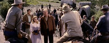 Movie still from “Jubal” (1956), directed by Delmer Daves – An old man and a young woman standing in front of an older man; Medium shot, Over the shoulder angle