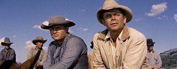 Movie still from “Jubal” (1956), directed by Delmer Daves – Two men wearing cowboy hats and sitting next to each other; Medium shot, Low angle