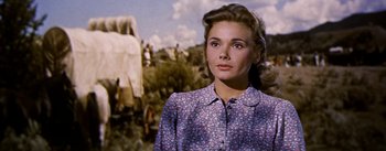 Movie still from “Jubal” (1956), directed by Delmer Daves – A woman in a floral shirt standing in front of an image; Close Up shot, Low angle