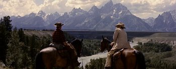 Movie still from “Jubal” (1956), directed by Delmer Daves – Two men on horseback ride through the mountains; Wide shot, Over the shoulder angle