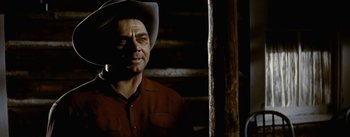 Movie still from “Jubal” (1956), directed by Delmer Daves – A man wearing a cowboy hat standing in front of a wooden wall; Close Up shot, Low angle