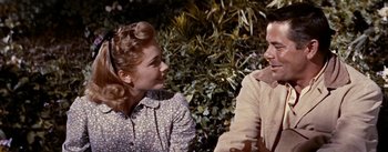 Movie still from “Jubal” (1956), directed by Delmer Daves – A woman and a man sitting next to each other in front of a bush; Close Up shot, Over the shoulder angle