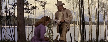 Movie still from “Jubal” (1956), directed by Delmer Daves – A man and a woman standing next to a body of water; Medium shot, Low angle