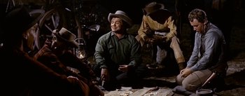 Movie still from “Jubal” (1956), directed by Delmer Daves – A group of people sitting on the ground with wine glasses; Medium shot, High angle