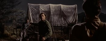 Movie still from “Jubal” (1956), directed by Delmer Daves – A man standing in front of a tent in the dark; Medium shot, Low angle