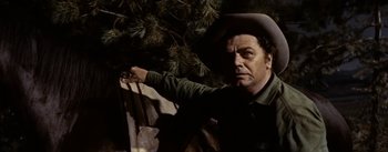Movie still from “Jubal” (1956), directed by Delmer Daves – A man wearing a cowboy hat standing next to a tree; Medium shot, Low angle