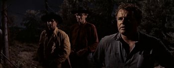 Movie still from “Jubal” (1956), directed by Delmer Daves – A group of men standing next to each other in the dark; Medium shot, Low angle