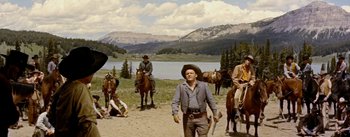 Movie still from “Jubal” (1956), directed by Delmer Daves – A group of people riding horses near a body of water; Wide shot, Low angle