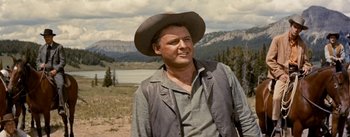 Movie still from “Jubal” (1956), directed by Delmer Daves – A man wearing a cowboy hat standing in a field; Medium shot, Low angle