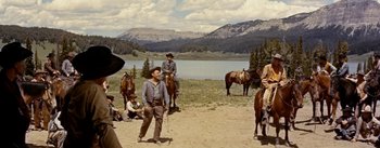 Movie still from “Jubal” (1956), directed by Delmer Daves – A group of men riding horses next to a body of water; Wide shot, Low angle