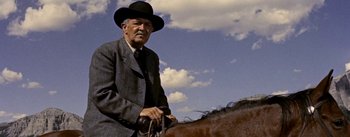 Movie still from “Jubal” (1956), directed by Delmer Daves – An older man in a suit and hat on a horse; Close Up shot, Low angle