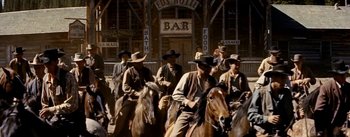 Movie still from “Jubal” (1956), directed by Delmer Daves – A group of men riding horses in front of a building; Wide shot, Low angle