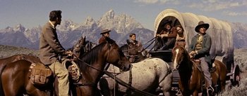 Movie still from “Jubal” (1956), directed by Delmer Daves – A group of people riding horses in a wagon; Wide shot, Low angle