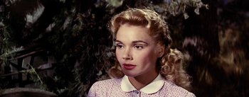 Movie still from “Jubal” (1956), directed by Delmer Daves – A woman with blonde curly hair wearing a pink dress; Close Up shot, Over the shoulder angle