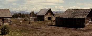 Movie still from “Jubal” (1956), directed by Delmer Daves – An old wooden barn with a wooden fence around it; Extreme Wide shot, High angle